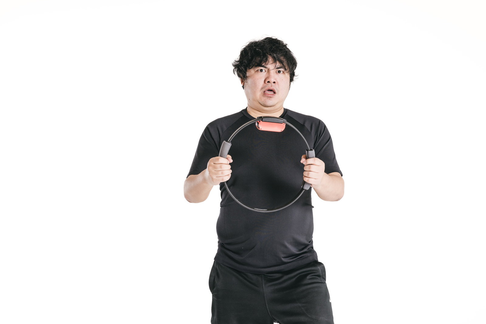 黒いTシャツを着た男性が体の前でリングフィットを握りしめてトレーニング中［モデル：段田隼人］