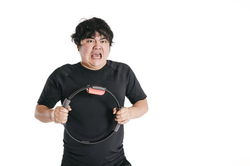 体の前でリングを持って表情豊かにトレーニングに励む男性