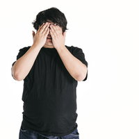 両手で顔を覆う黒いTシャツの男性ポートレートの写真