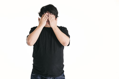 両手で顔を覆う黒いTシャツの男性ポートレート