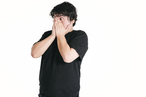 驚きのあまり両手で口を覆う男性のショック表現