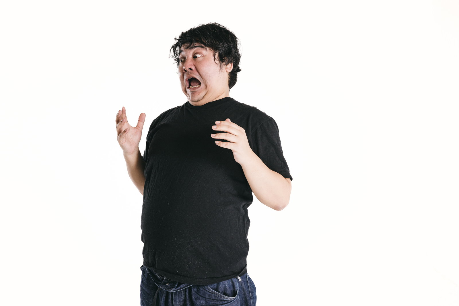 黒いTシャツを着た男性が驚いた表情で両手を広げている［モデル：段田隼人］