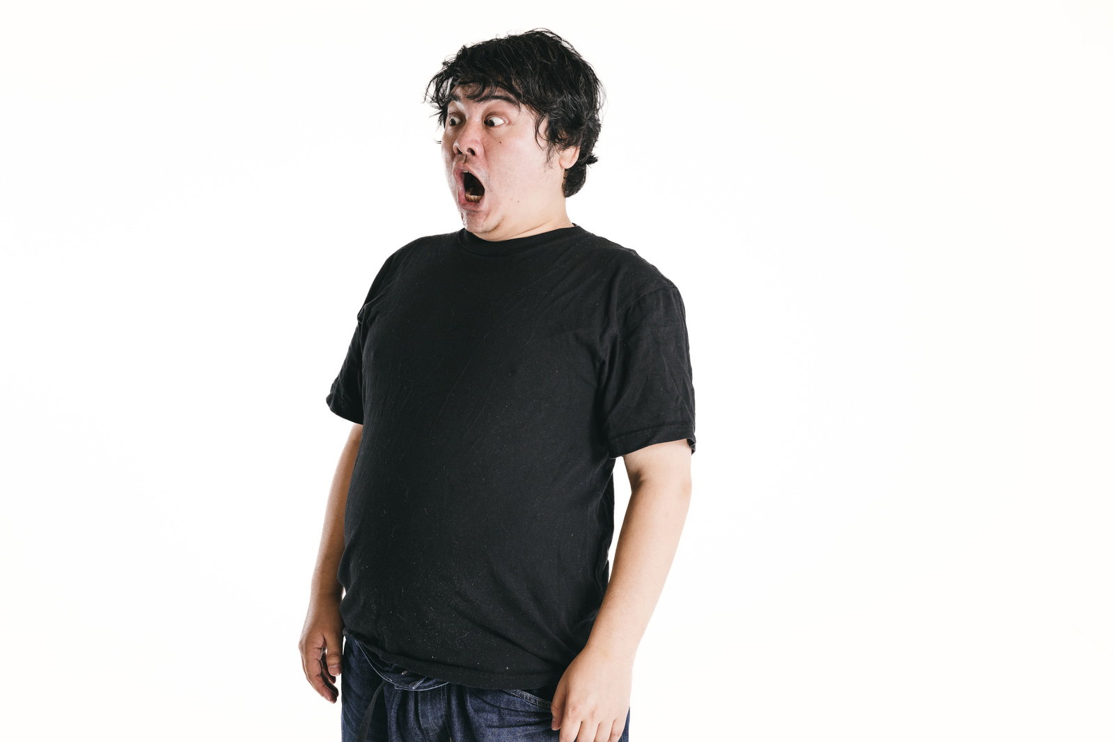 口を開けて驚く男性が黒いTシャツとジーンズを着て上を向いている［モデル：段田隼人］