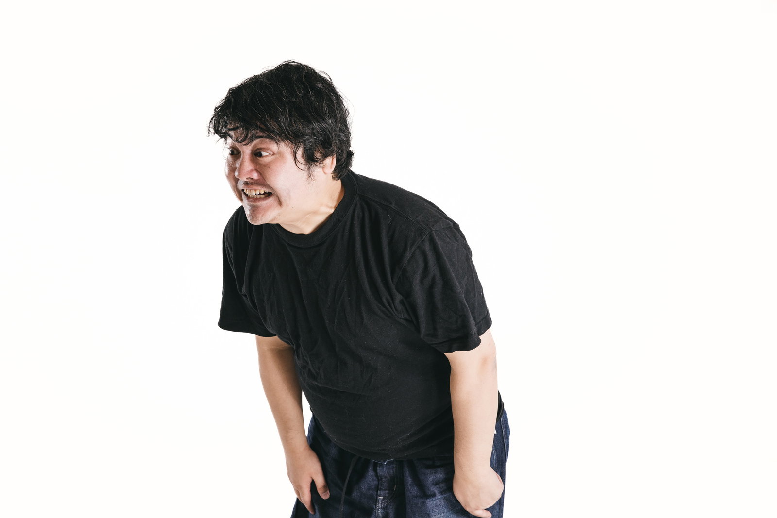 黒いTシャツを着た男性が前かがみになり、威嚇するような表情で口を開けている［モデル：段田隼人］