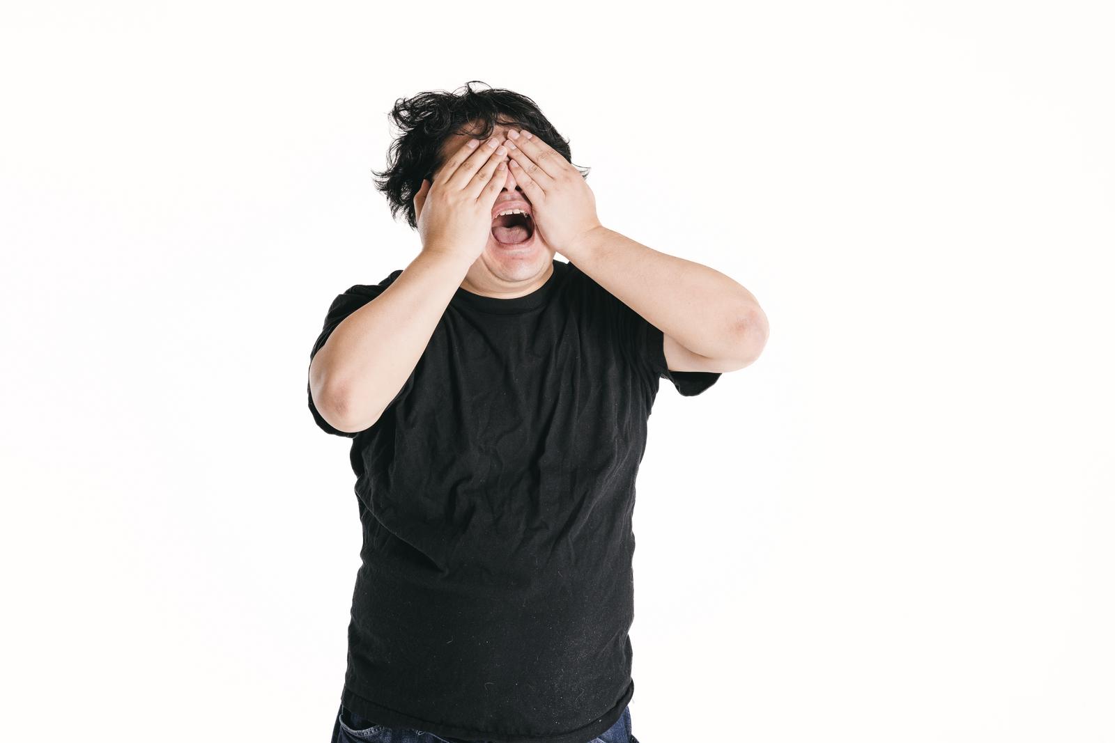 両手で目を覆い開いた口で悔しさを表現する男性［モデル：段田隼人］