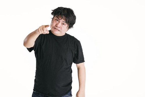 黒いTシャツの男性が指差しで威嚇する表情