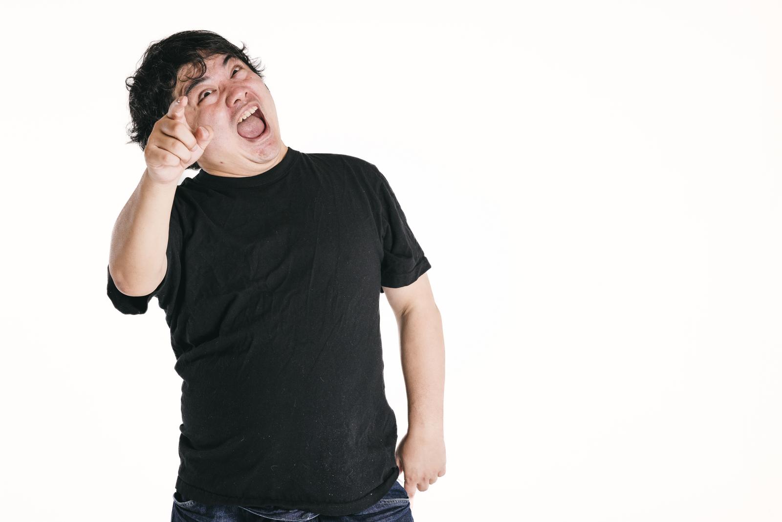 黒いTシャツを着た男性が指差しをしながら威嚇的な表情で煽っている［モデル：段田隼人］