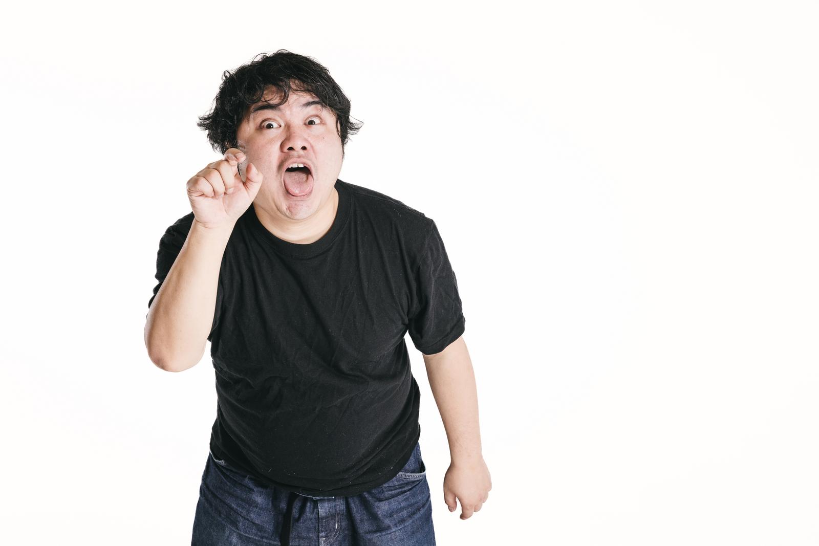 指を指して笑う男性。人を小馬鹿にする仕草をしている［モデル：段田隼人］