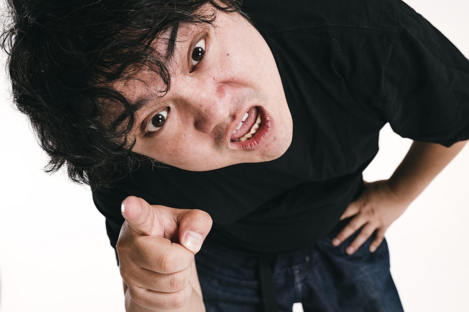黒いTシャツの男性が指差しして挑発的に近づいてくる様子［モデル：段田隼人］