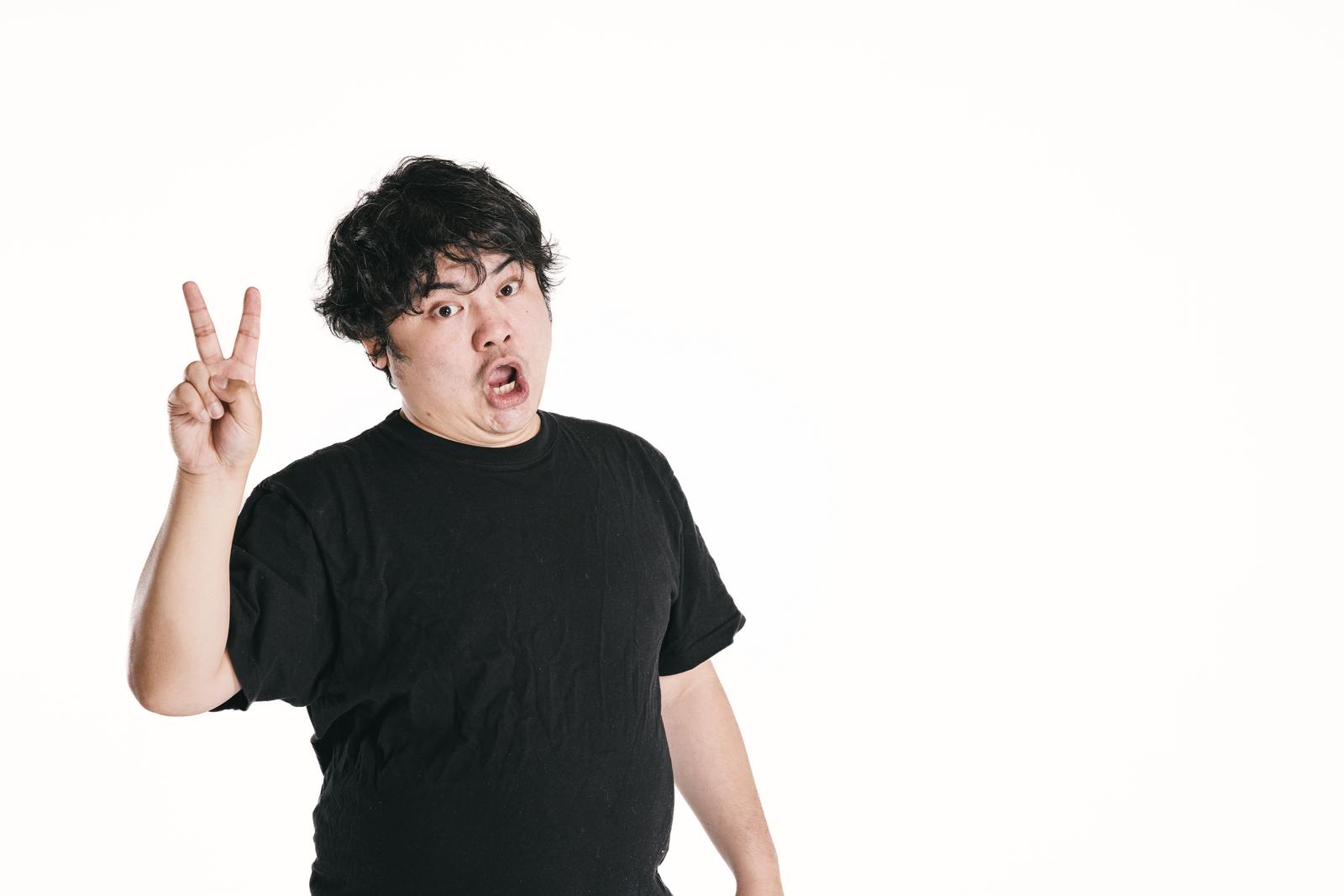 ピースサインをしながらイエーイと叫ぶ黒いTシャツの男性［モデル：段田隼人］