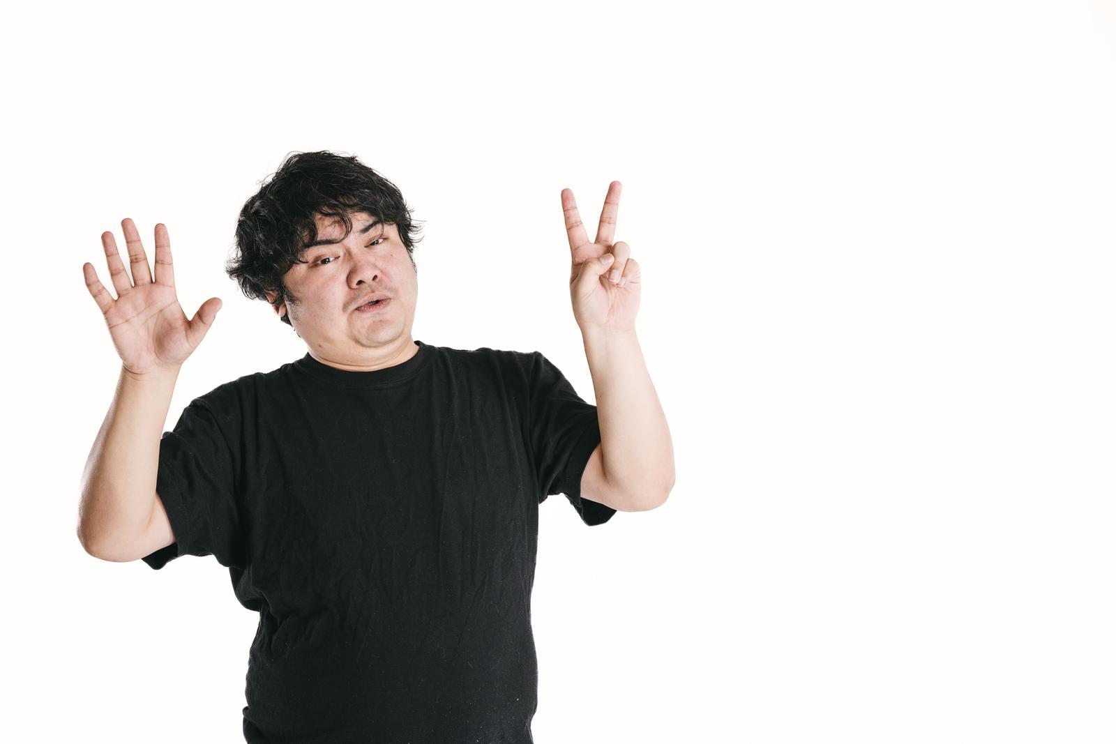 黒いTシャツの男性がハンドサインで7番を表現している［モデル：段田隼人］