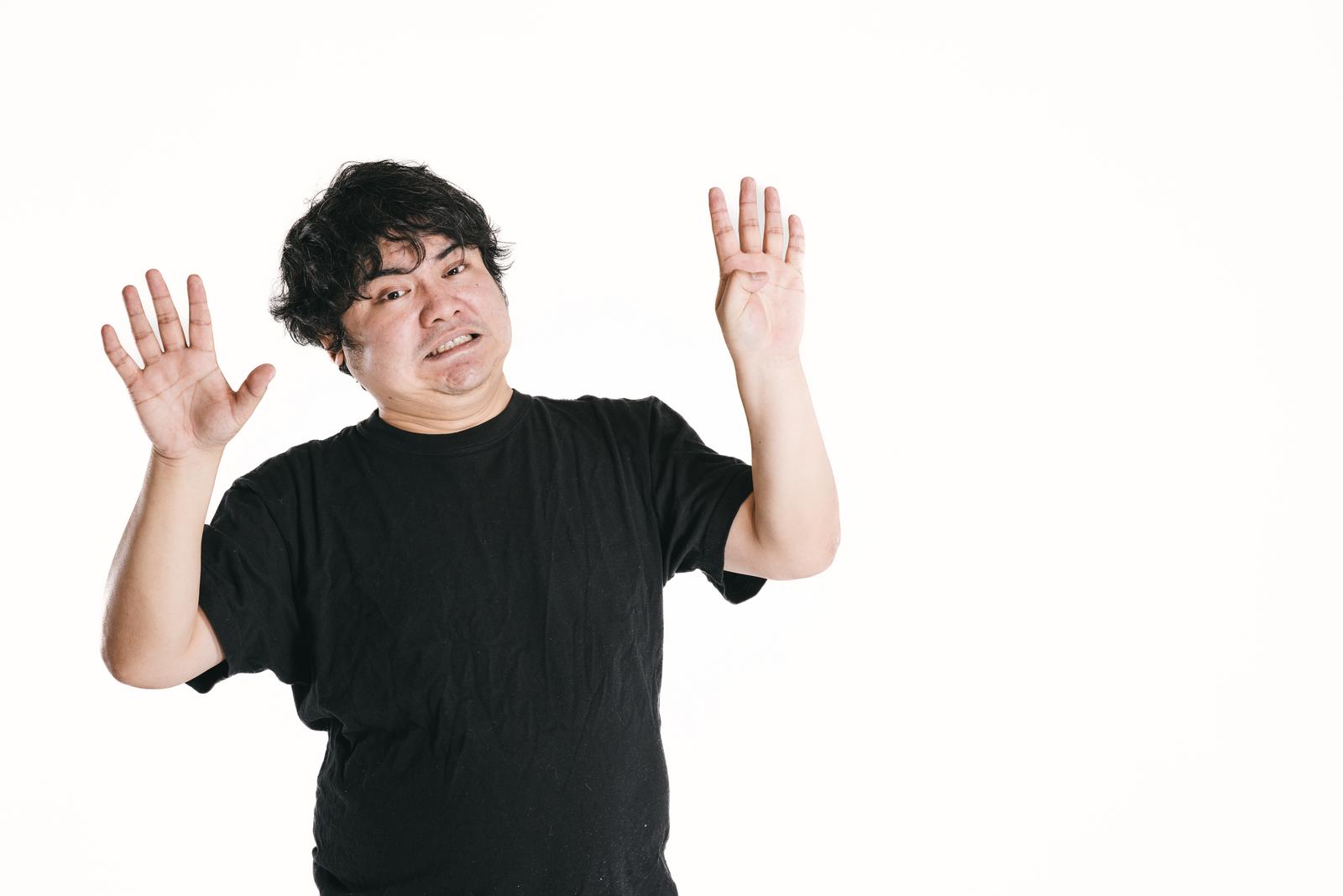 両手の指を広げて数字の9を表現しながら笑う黒いTシャツの男性［モデル：段田隼人］