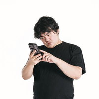 スマートフォンを見つめながら首を傾げる男性の写真