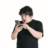 スマートフォンの画面を凝視して驚く男性の反応の写真