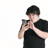 黒いTシャツを着た男性がスマートフォンの画面を凝視して驚く瞬間の写真