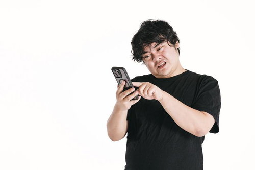 スマートフォンの画面を見ながら苦悩する男性