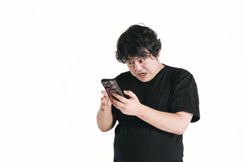 スマホゲームに夢中で目を見開く男性