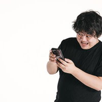 スマホの画面を見て目を見開く驚く男性のリアクションの写真