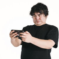 男性が両手で持つスマートフォンに見入る真剣な表情の写真