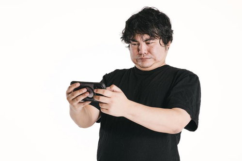 男性が両手で持つスマートフォンに見入る真剣な表情