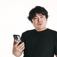スマホを片手に持ち目を丸くする驚いた表情の男性の写真