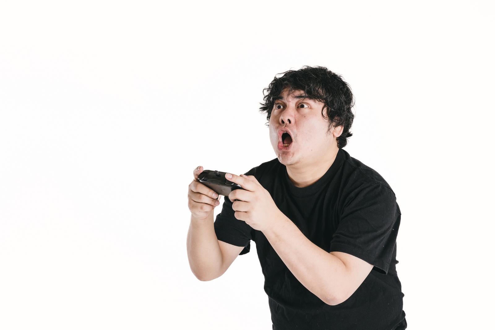 ゲームコントローラーを持ち驚く男性