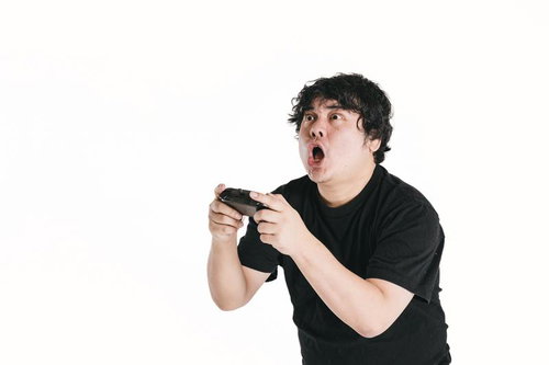 驚愕のリアクションをしながらゲームコントローラーでゲームをプレイする男性