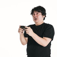 ゲームコントローラーを握りながら目を見開く男性の写真