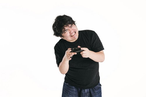 コントローラーを両手で握りしめ身をよじって歯を食いしばる男性