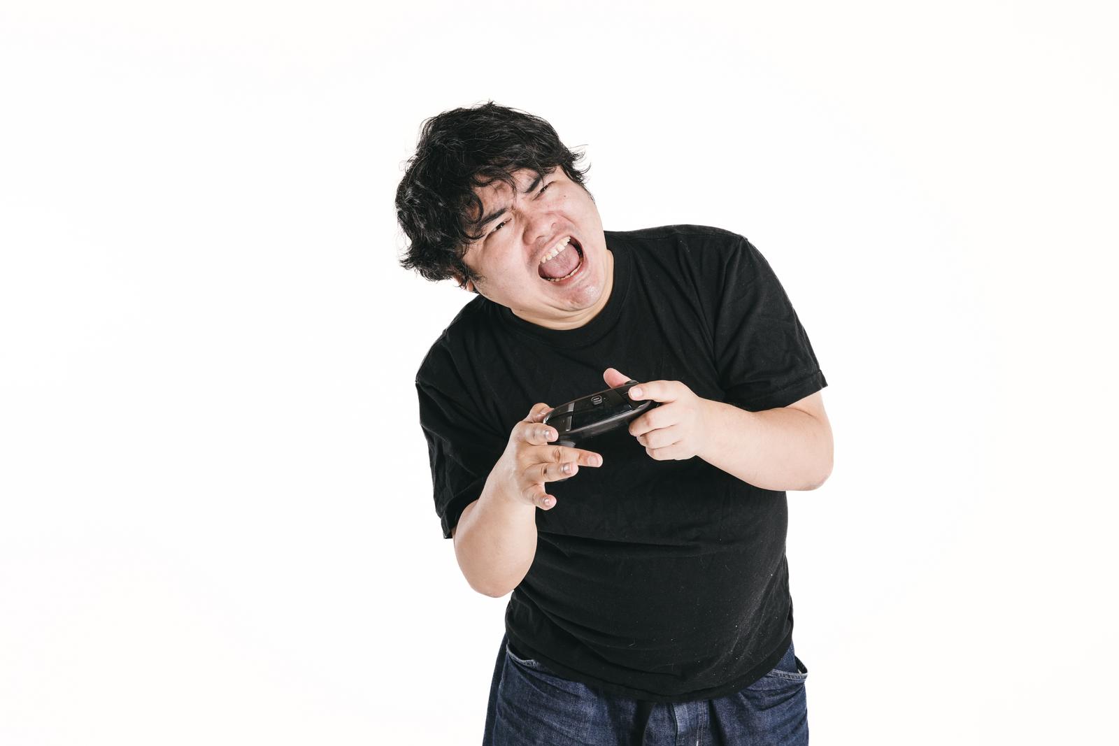 ゲームコントローラーを握りながら身悶えて悔しがる男性［モデル：段田隼人］