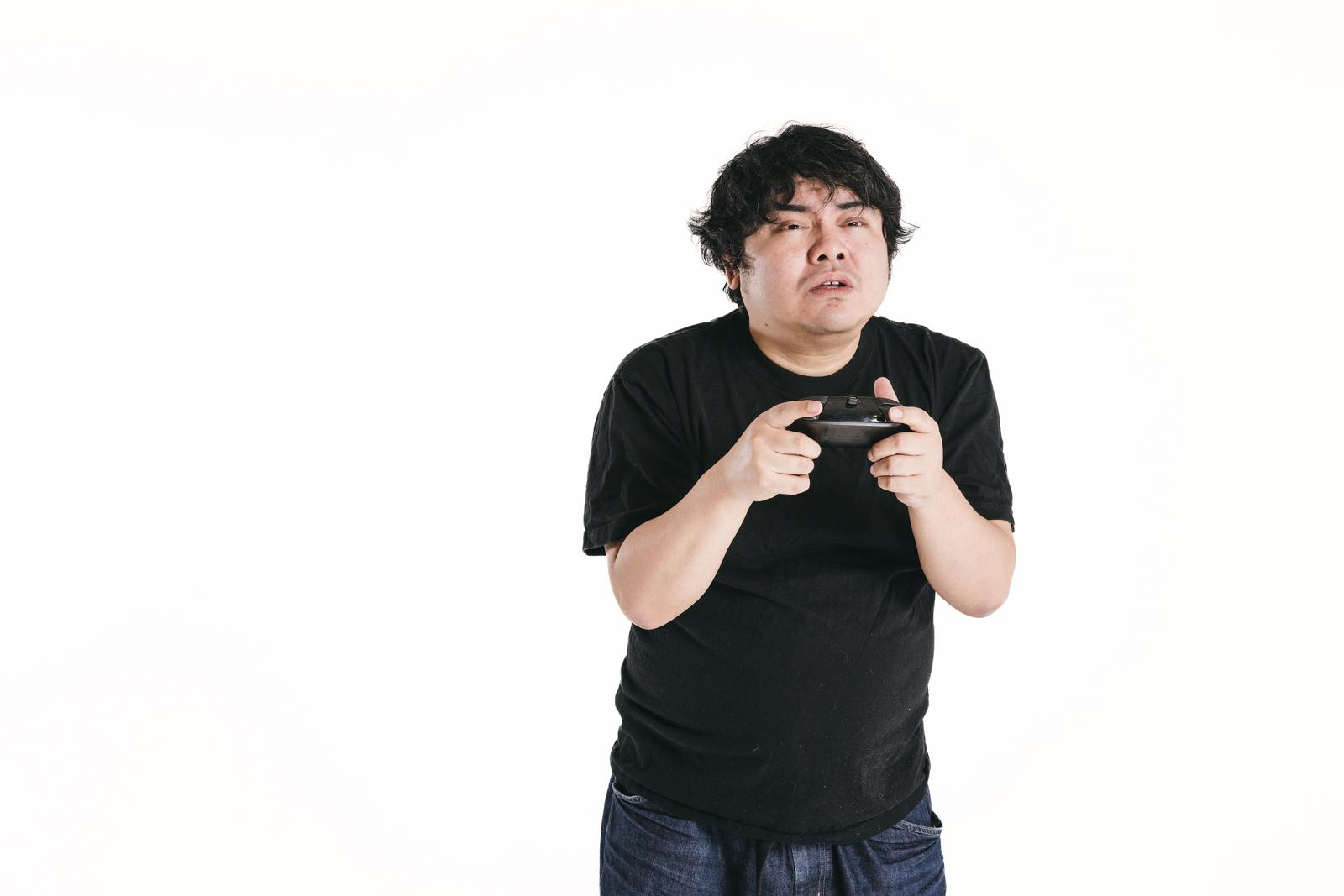 黒いTシャツを着た男性がゲームコントローラーを握りながら画面に没頭している［モデル：段田隼人］