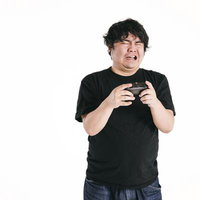 ゲームコントローラーを握りしめ失望の表情を浮かべる男性の写真