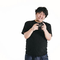 ゲームコントローラーを握りしめて歯を食いしばる男性の写真