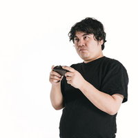 ゲームコントローラーを握り集中力全開でプレイする男性の写真