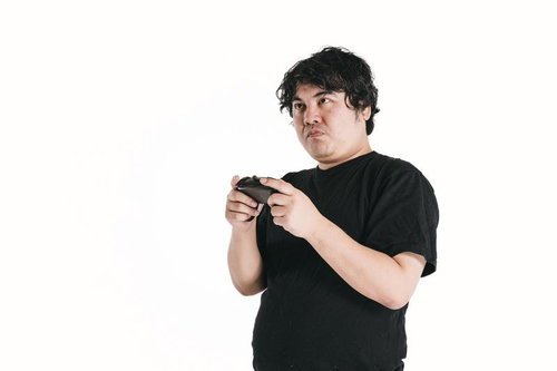 ゲームコントローラーを握り集中力全開でプレイする男性