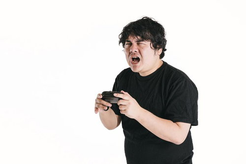 予期せぬ敗北に目を細めてゲームコントローラーを握る男性