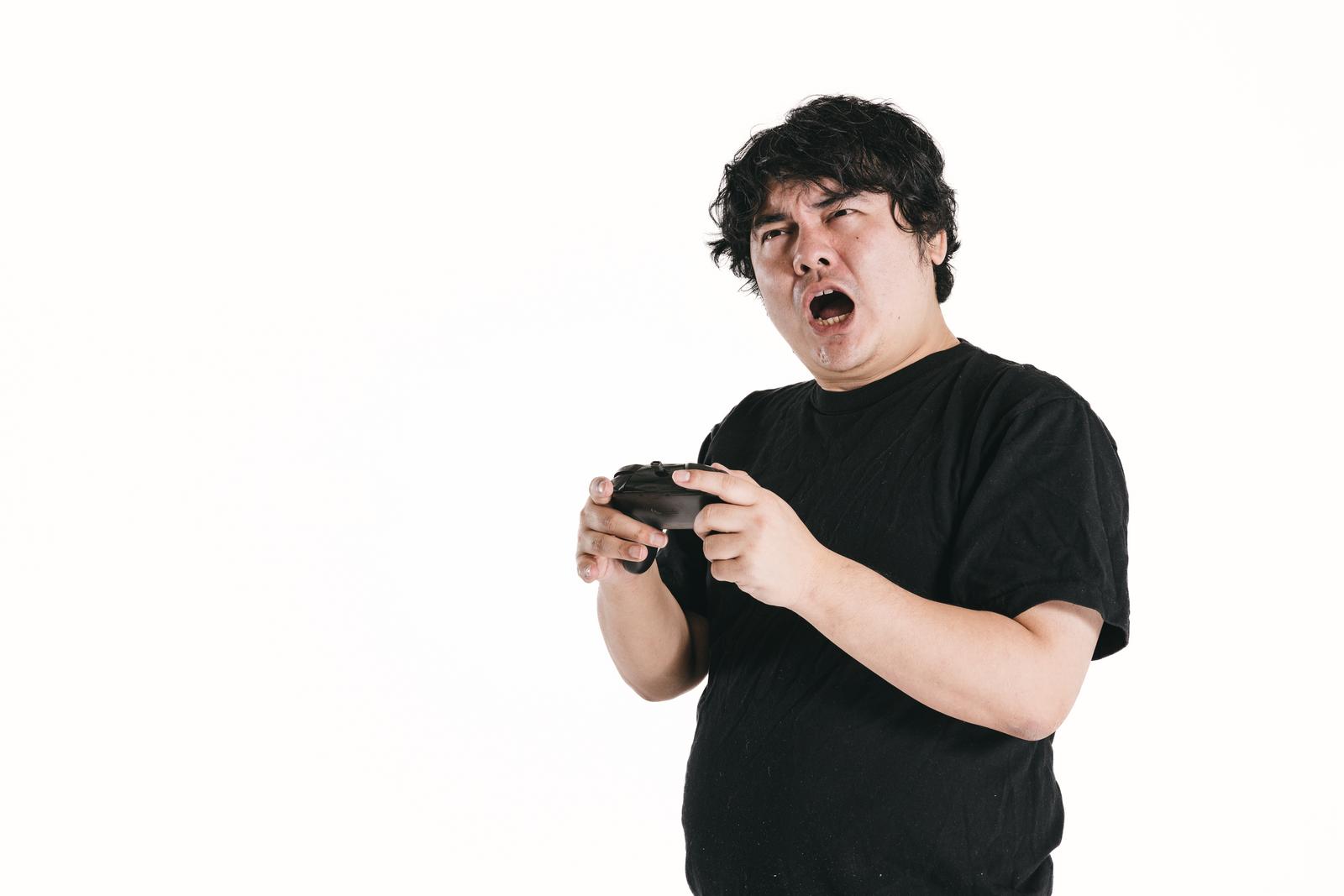 ゲームコントローラーを握り苦い表情をする男性［モデル：段田隼人］