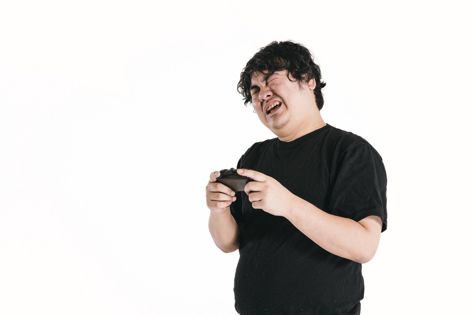 ゲームコントローラーを握ってしかめっ面をする男性ゲーマー［モデル：段田隼人］