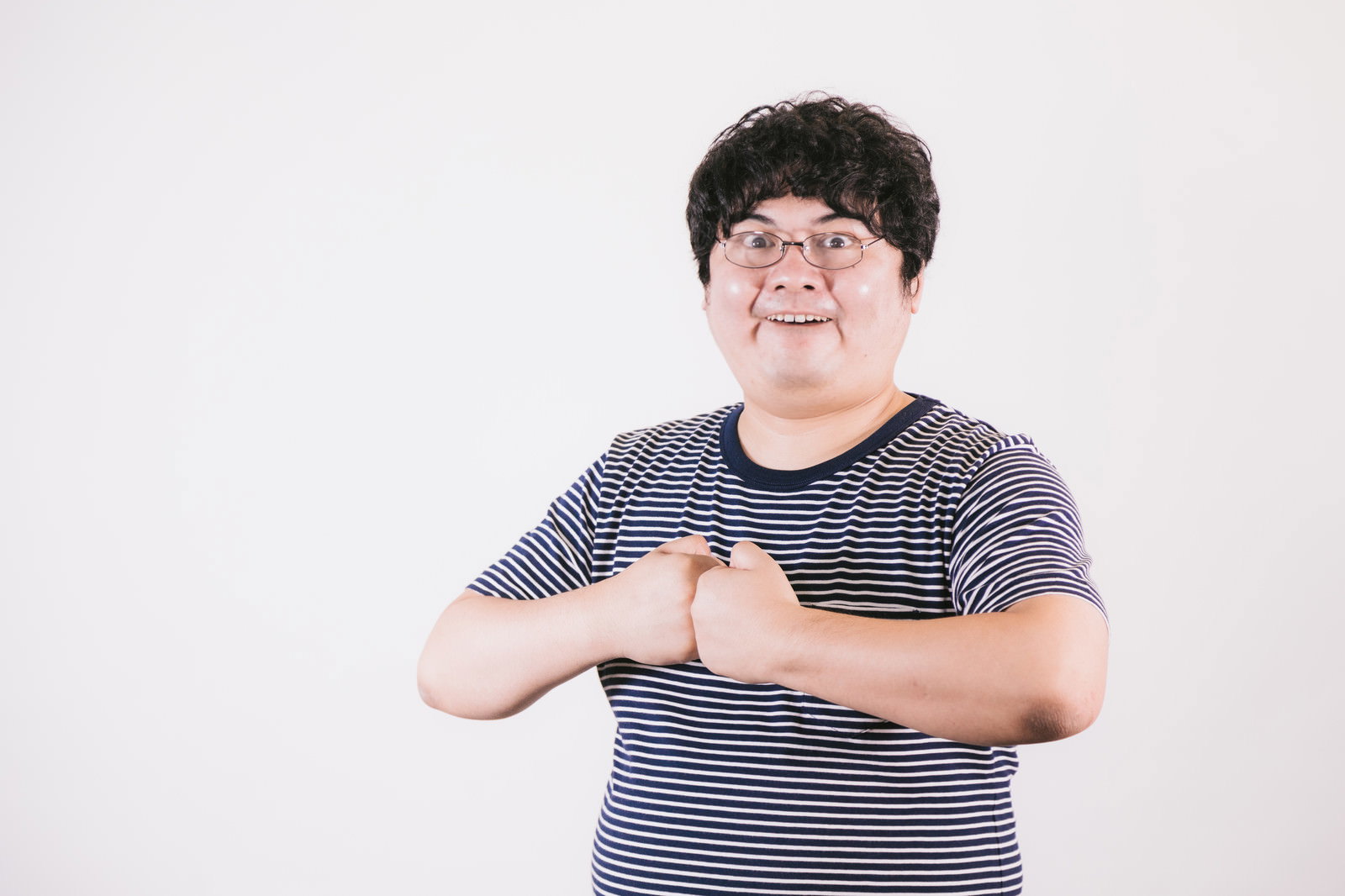 拳を構えて威嚇するような表情を見せるボーダーシャツの男性［モデル：段田隼人］