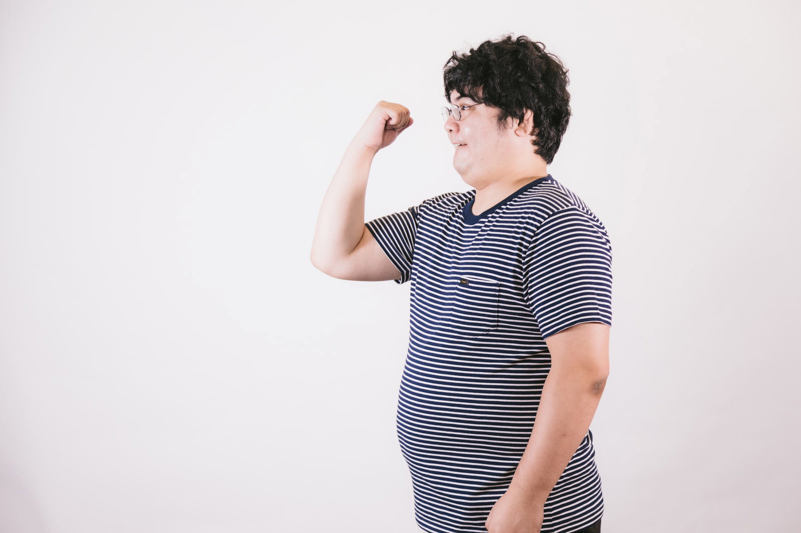 ボーダーのTシャツを着た男性が右手で拳を握り上げているポーズ［モデル：段田隼人］