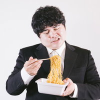 エンジニアなのにソース焼きそば作らされて不満な男性の写真