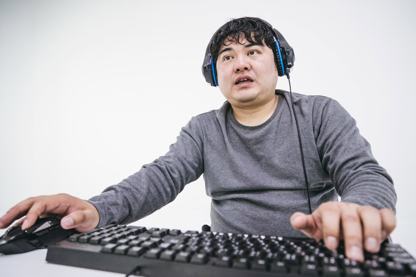 ヘッドセットを装着してキーボードに手を置く男性［モデル：段田隼人］