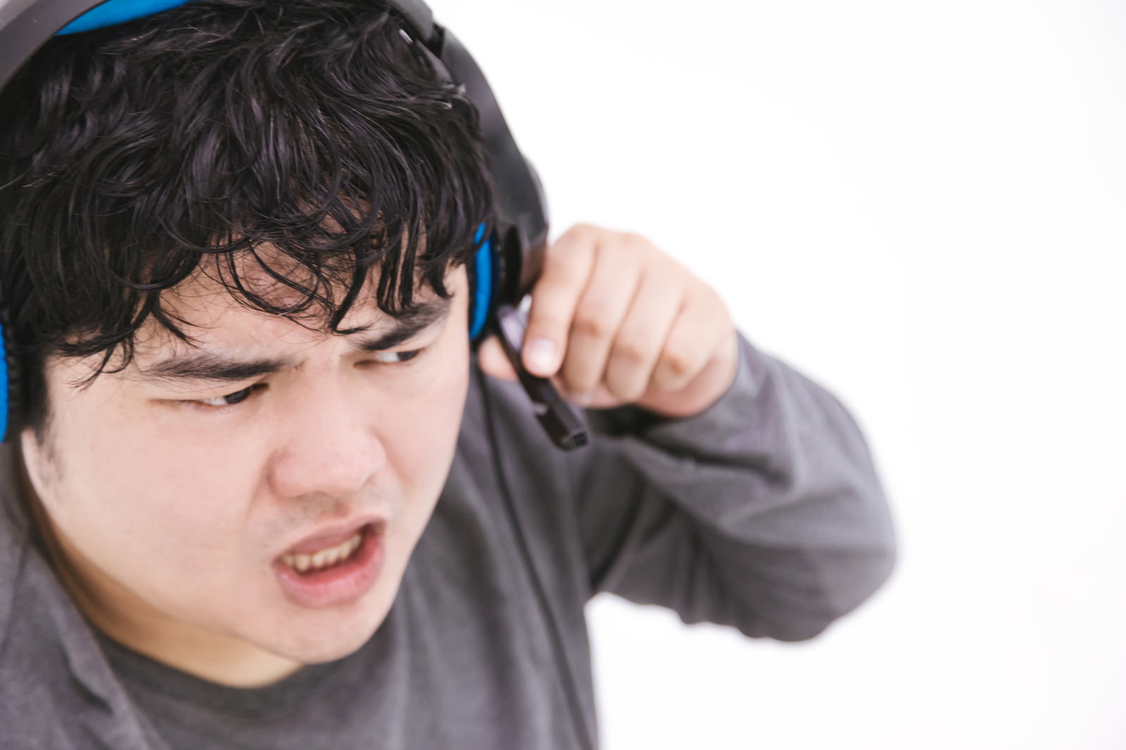 ヘッドセットを装着して音声チャットで激怒する男性プレイヤー［モデル：段田隼人］