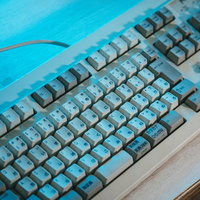 青いライトに照らされた分厚い昔のキーボードの写真