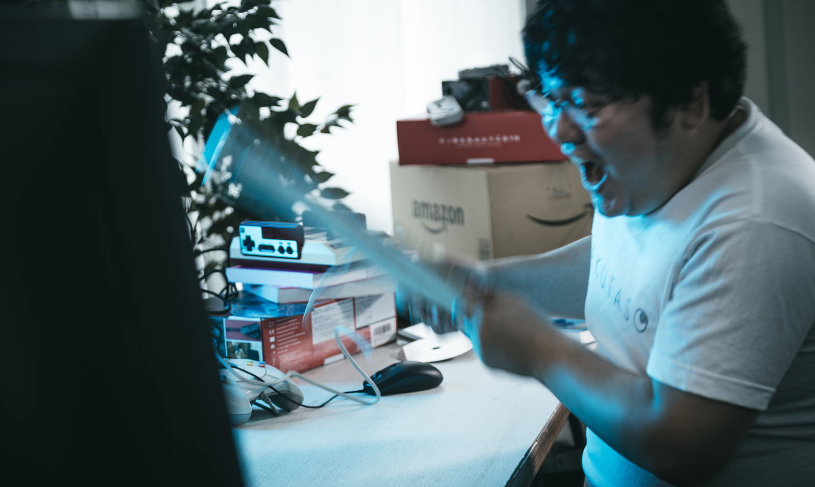 パソコンゲーム中に激怒し、キーボードを叩く男性がデスクで身体を動かしている様子［モデル：段田隼人］