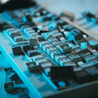 キートップが散乱する無残なキーボード、青い照明に照らされた破壊風景の写真