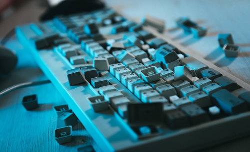 キートップが散乱する無残なキーボード、青い照明に照らされた破壊風景
