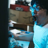 パソコンの前で叫ぶ男性の写真