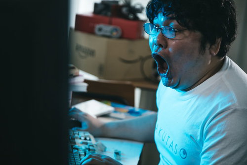 パソコンの前で叫ぶ男性