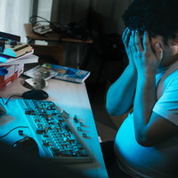 青いLED照明の下で頭を抱える男性の写真